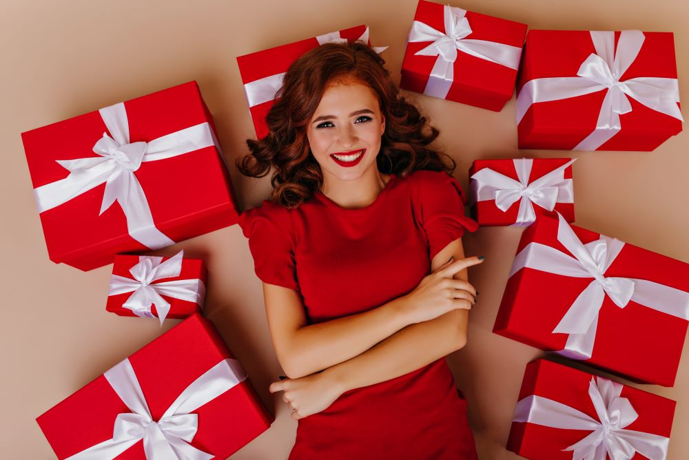 graceful-curly-woman-good-mood-posing-floor-with-gifts-attractive-female-model-enjoying-christmas-party